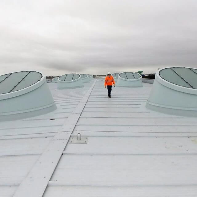 Commercial roof penetrations, with man on roof inspecting